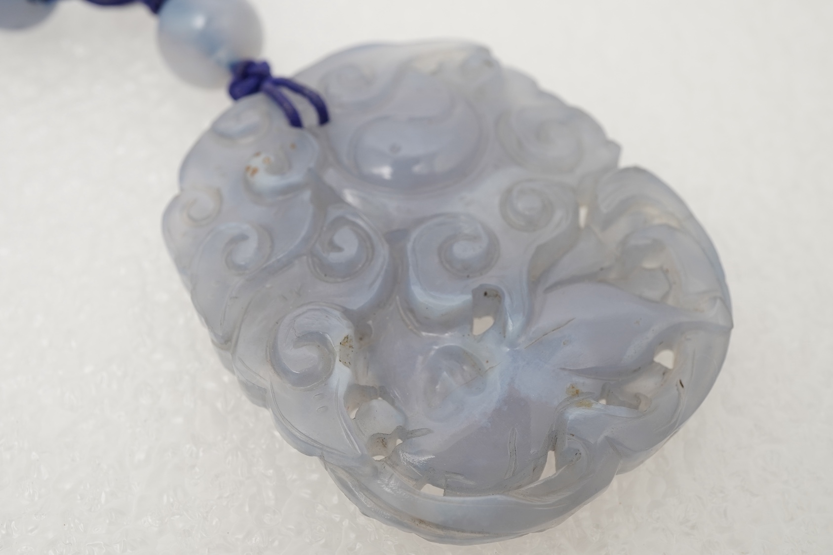 A Chinese jade ‘spirit lock’ plaque, a jadeite bead necklace and a blue quartz bead necklace, 20th century